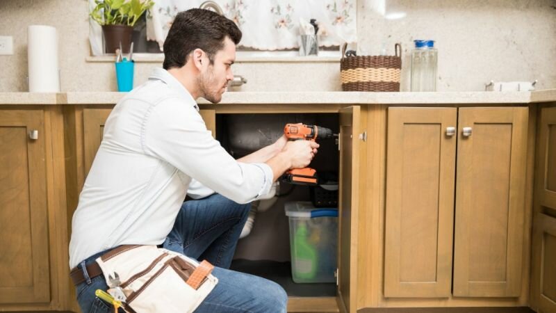 Handy man repairing cabinet