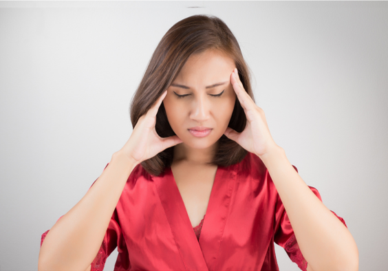 Lady in foreclosure wearing red top holding aching head with hands