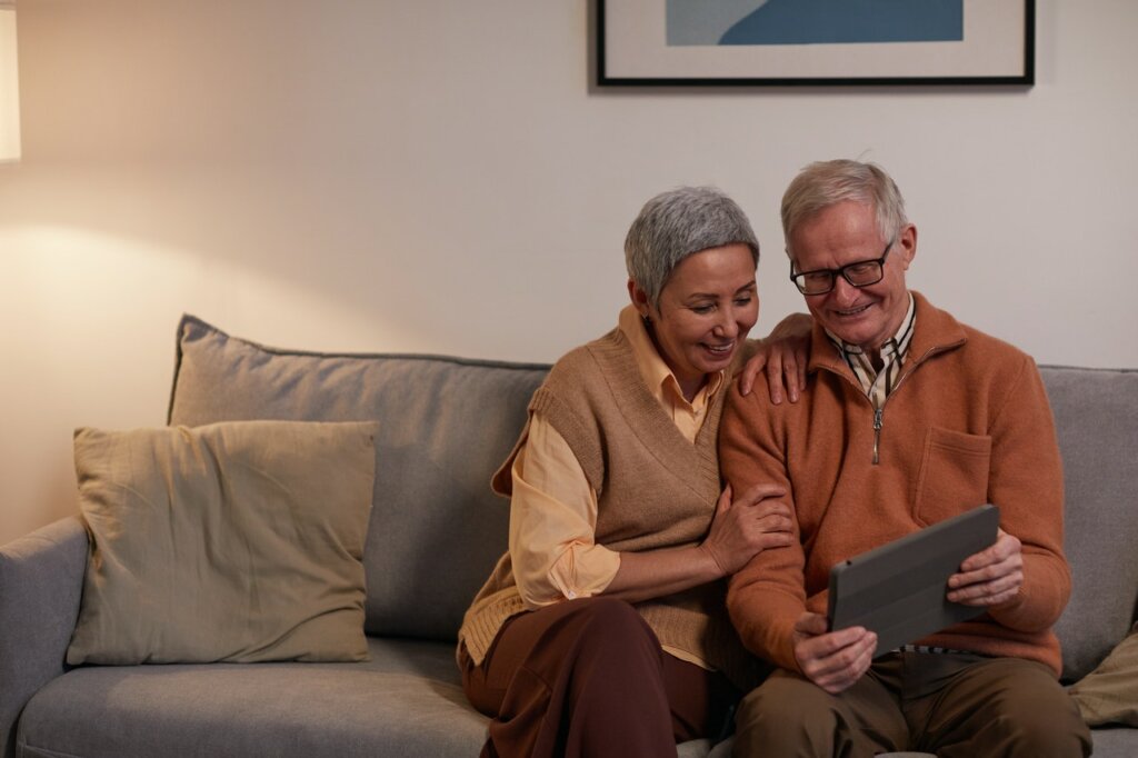 Two older adults looking at a tablet, thinking about the biggest reasons to downsize your home as a senior in Spartanburg