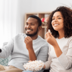 Two young homeowners eat popcorn while watching some of the best HGTV home renovation shows