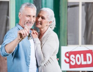 (couple standing in front of their Sold sign handing over the keys to their house) Sell My House As-Is Fast. Contact Midwest Fix-and-Flip today!