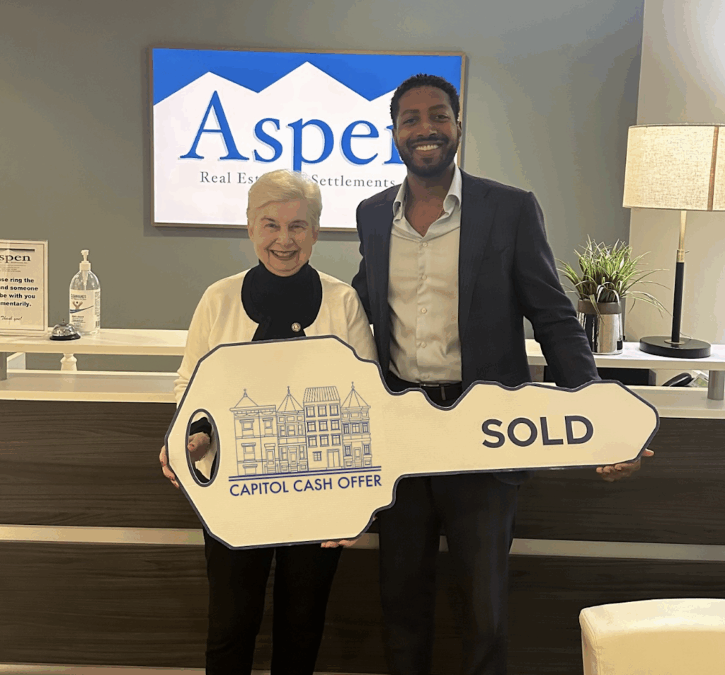 Satisfied homeowner holding a “Sold” sign with Capitol Cash Offer after a successful cash home sale