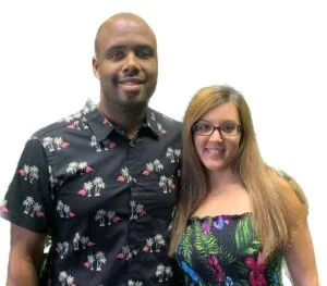 The owner of R&H Distressed Properties and his wife smiling together in laid-back clothing, standing casually to reflect a friendly, approachable, and family-run business atmosphere. We buy houses for cash. Sell my house fast