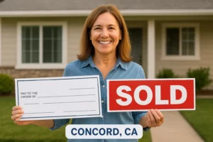 Happy homeowner in Concord, CA smiling while holding a large check and a red "SOLD FAST" sign in front of her house, representing cash home buyers. Sell My House Fast.