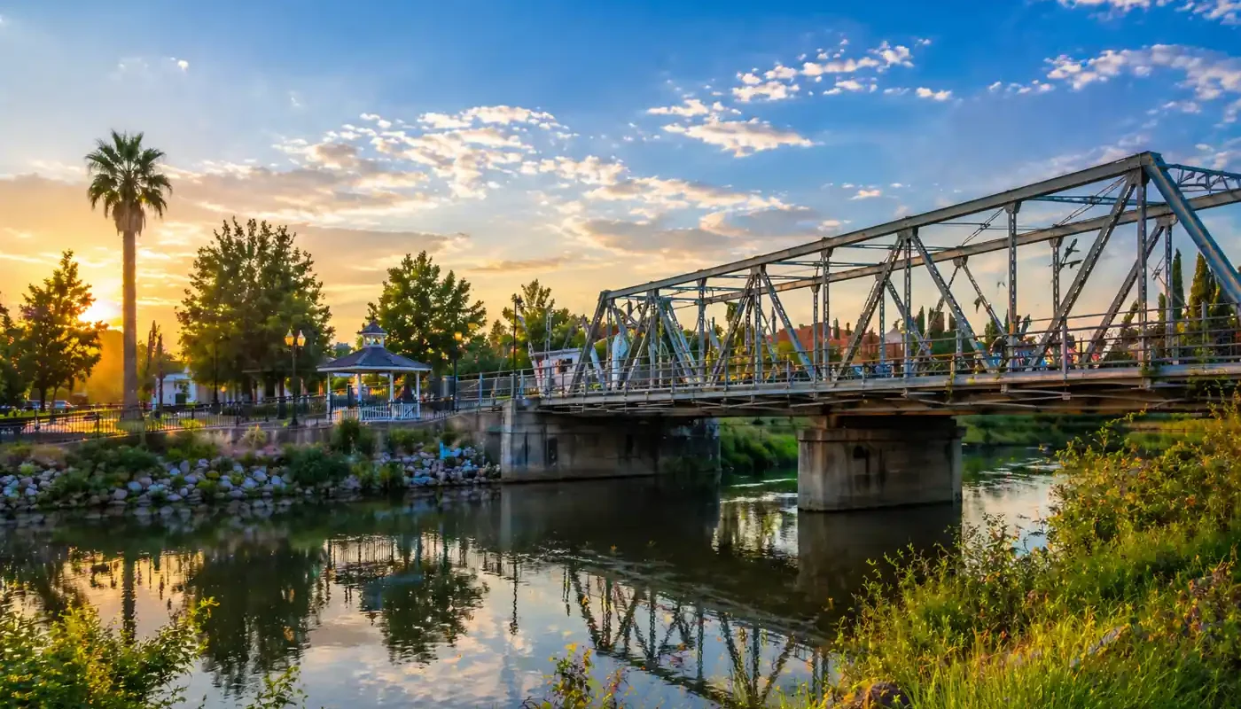 Scenic river view with bridge and trees at sunset in Yuba City CA, quiet neighborhood where we buy houses and help homeowners sell their house fast