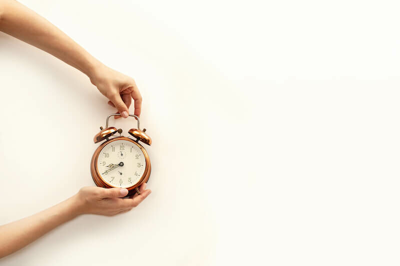 Hand holding bronze watch on white paper background