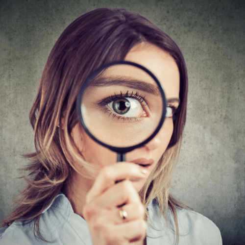 curious girl looking through a magnifying glass