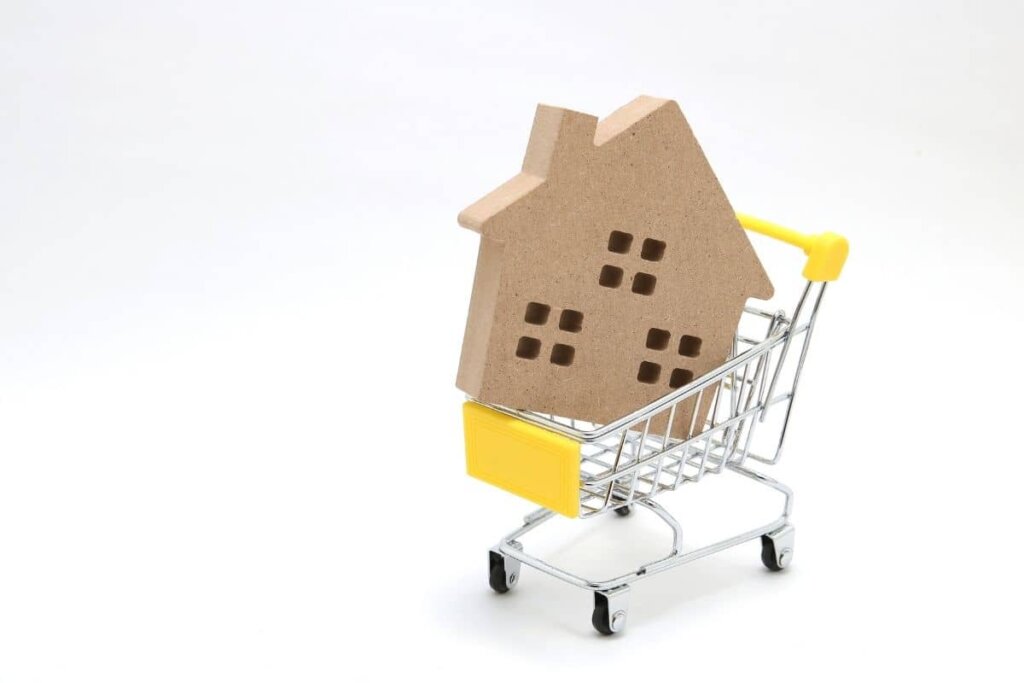 A little wooden house in a shopping cart.  Want to buy a house?