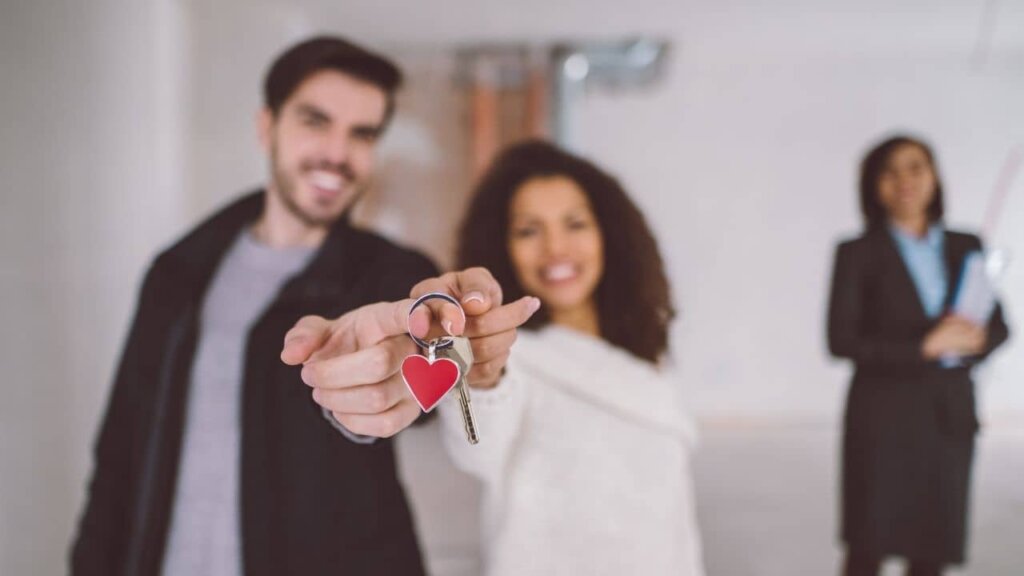 A couple holding together the key to their new home with a heart key chain. 