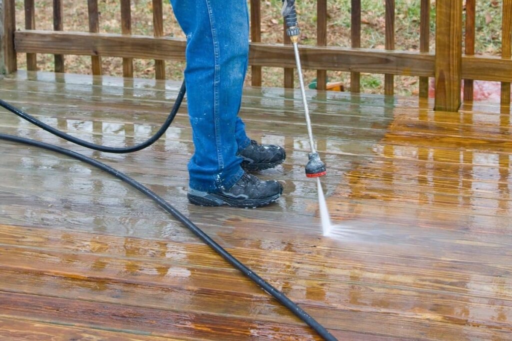 a man pressure washing a wood deck.