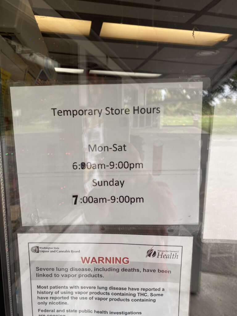 Sign on the front door of Lake Goodwin Store showing the store hours.