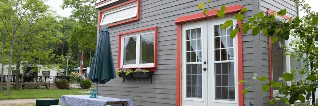 gray mobile home with red trim set around trees