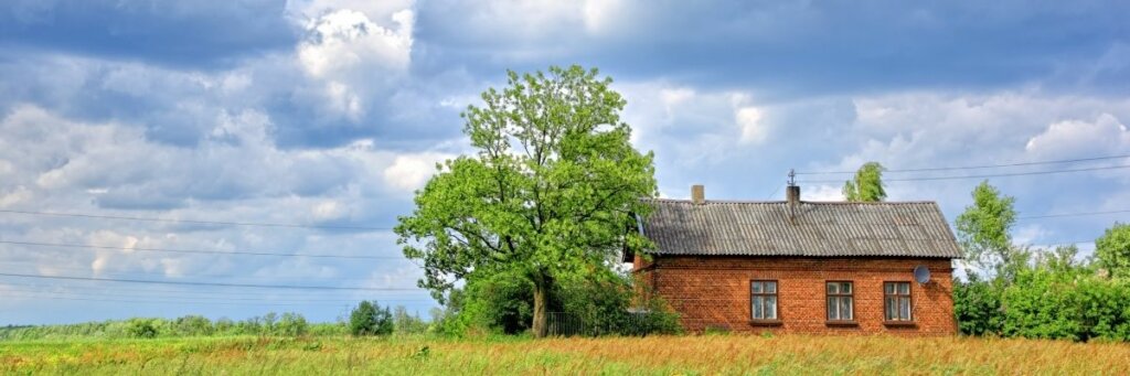 Single brick house surrounded by green land