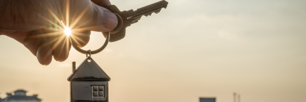 a key with a house key chain being shown agaisnt the backdriop of the sky