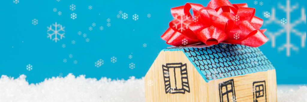 a little wooden toy house with a red bow on top