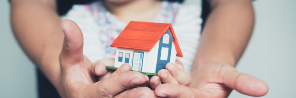 little toy house in the hands of an child and an adult