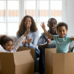 Happy african american parents and kids playing in boxes moving out of Houston