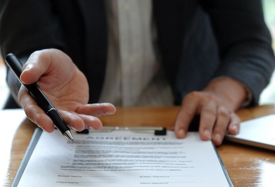 Businessmen selling the house pointing at the signing of the sales contract in the office.