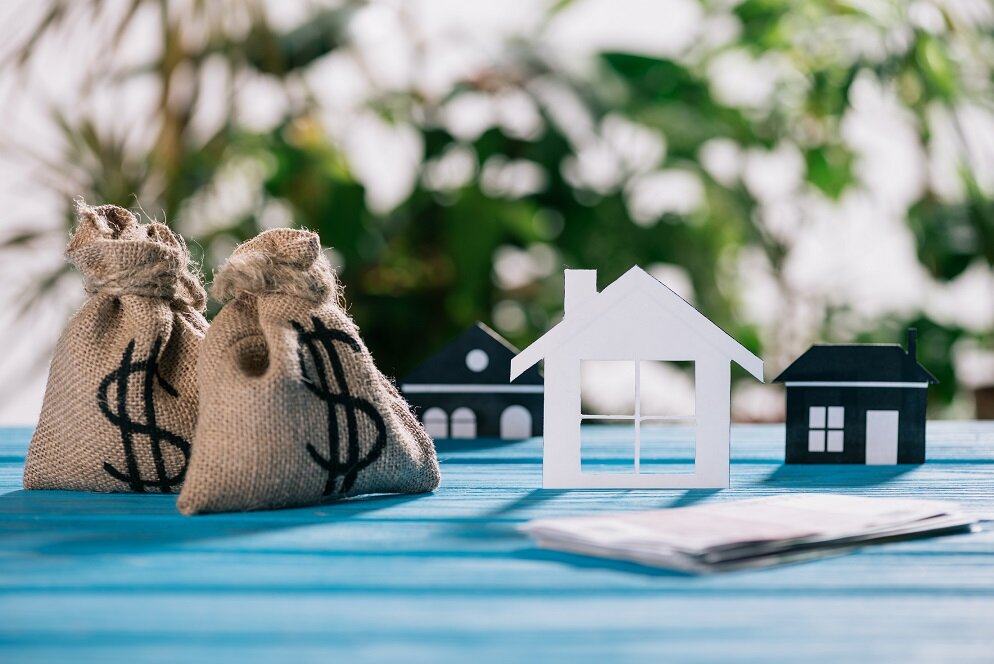 selective focus of paper houses and moneybags with dollar signs on wooden desk, mortgage concept