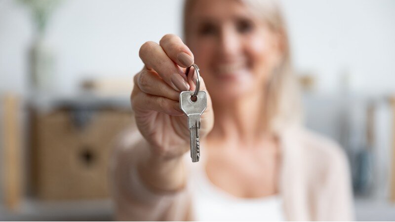 A real estate investor showing a house key.