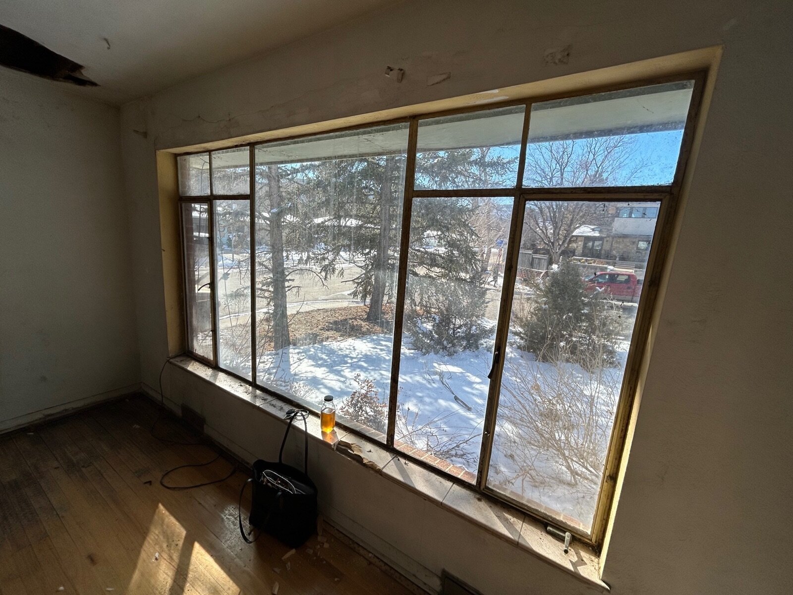 inside the original house at 2700 15th St in Boulder before we rebuilt — bare floors, old single-pane picture window, peeling ceiling