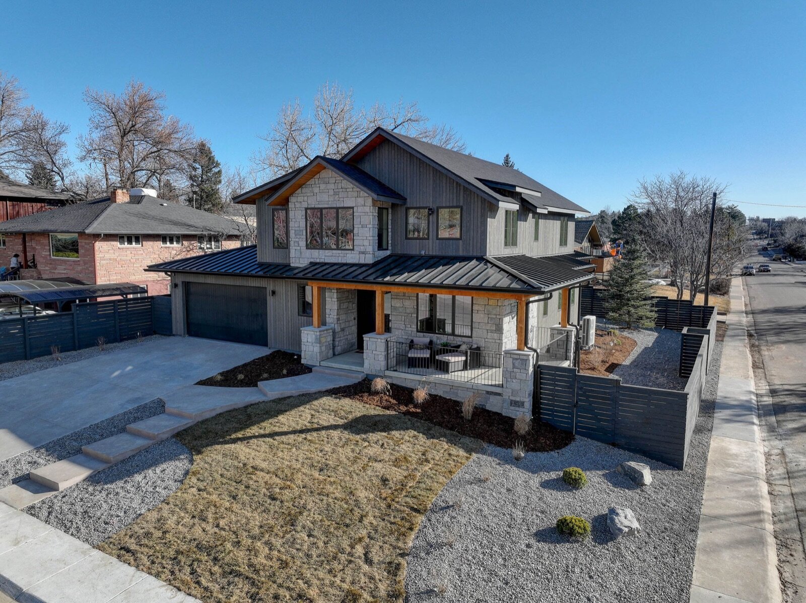 the new home Janis Development designed and built on that same Boulder lot at 2700 15th St — gray siding, stone, covered timber porch