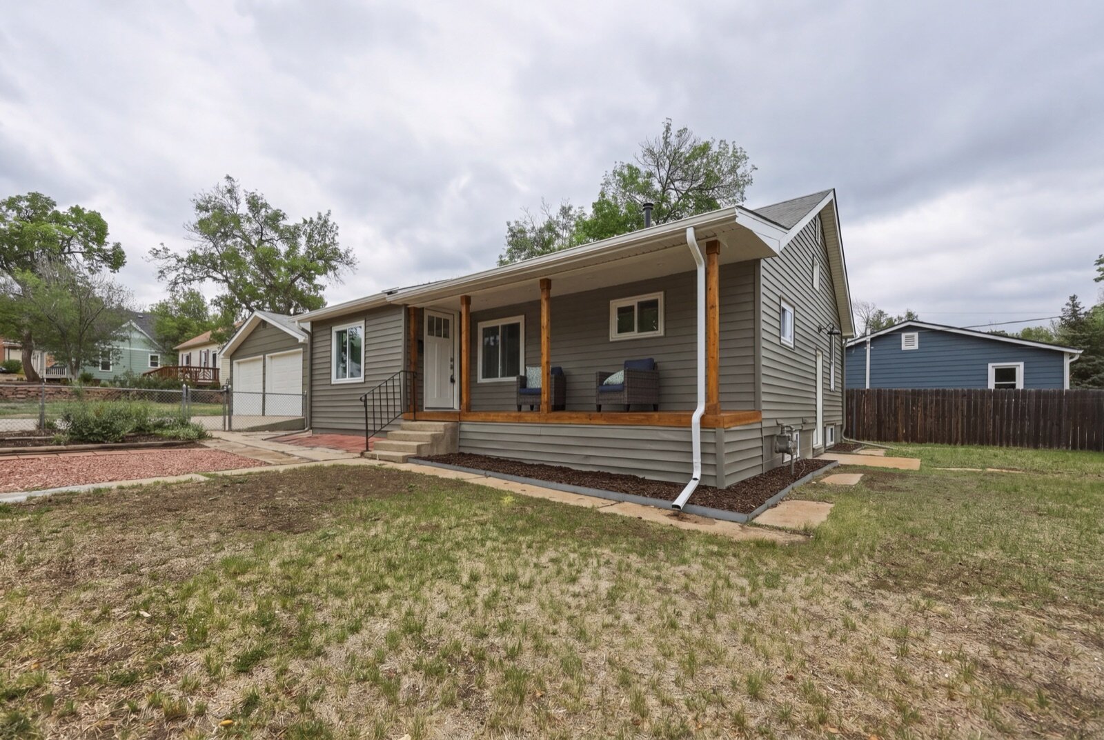 the same Bowen St house in Longmont after our full renovation — new gray siding, covered timber front porch, new windows and landscaping