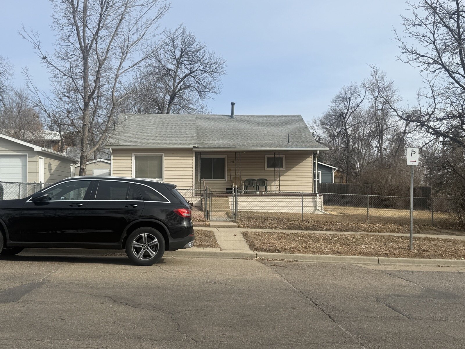 older Longmont bungalow on Bowen St before renovation — original tan siding, chain-link fence, bare winter yard