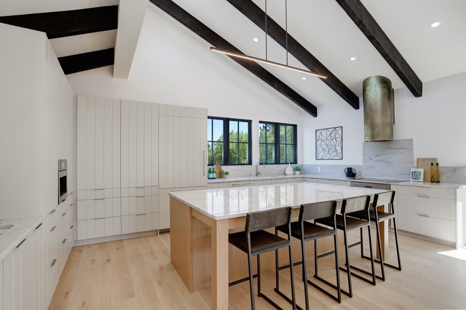 the same Juilliard St kitchen in Boulder after our gut rehab — vaulted ceiling, black beams, white cabinetry