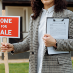 A realtor placing a "Home For Sale" sign in front of a property