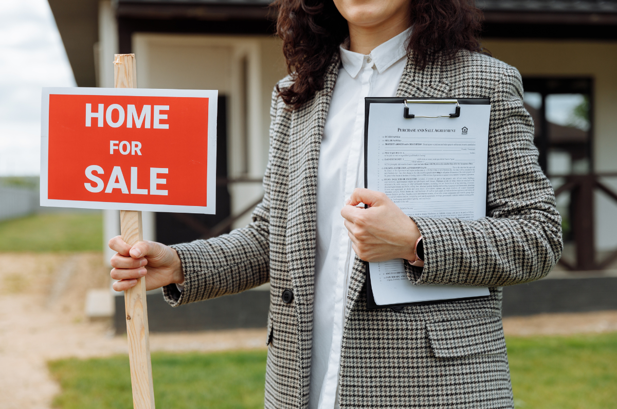 A realtor placing a "Home For Sale" sign in front of a property