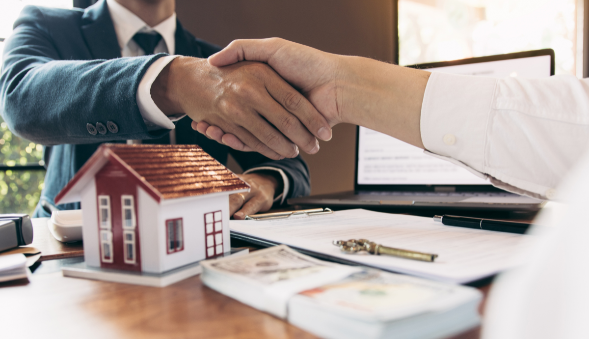 Hands shaking over real estate contracts