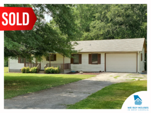 A ranch-style house with white siding, brown trim, and large tree in the front yard [bought by We Buy Houses in West Georgia]