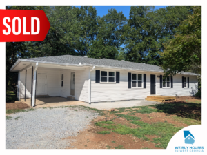 A ranch-style house with white siding, black trim, and a carport [bought by We Buy Houses in West Georgia]