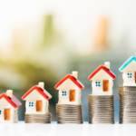 Real estate investment stock photo - house figurines on top of stacks of coins