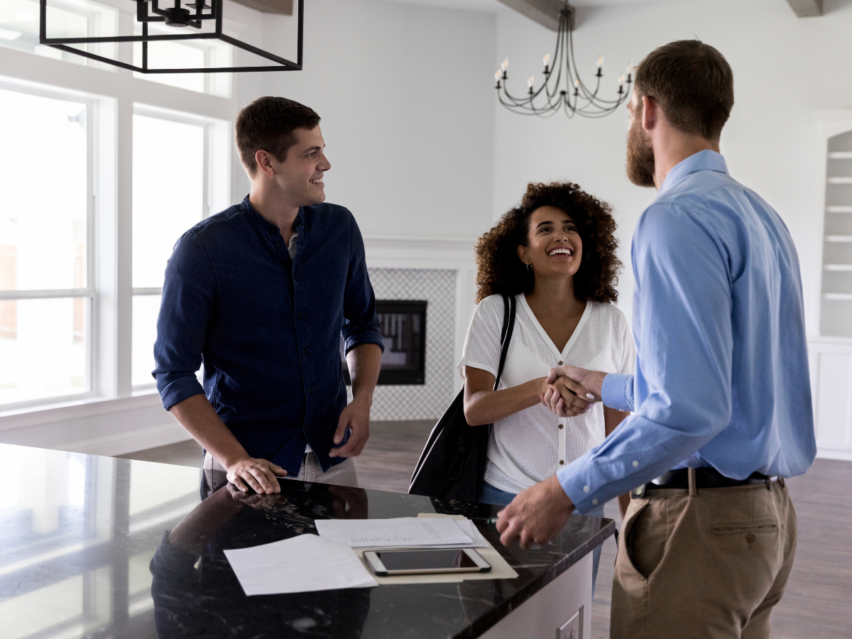 A couple shaking hands with a realtor in a flipped house