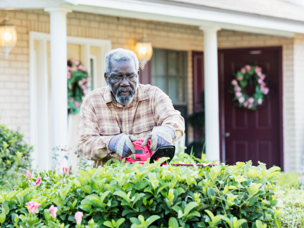 A man trimming hedges in front of his house