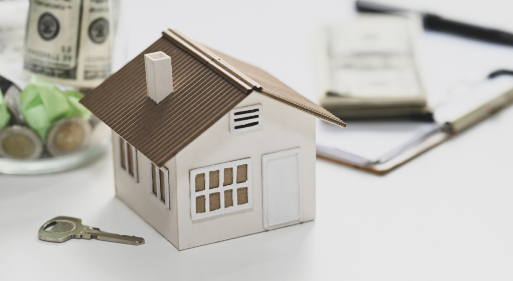 Stock image for inherited property: a small house figurine beside a key, a stack of money, and a clipboard.