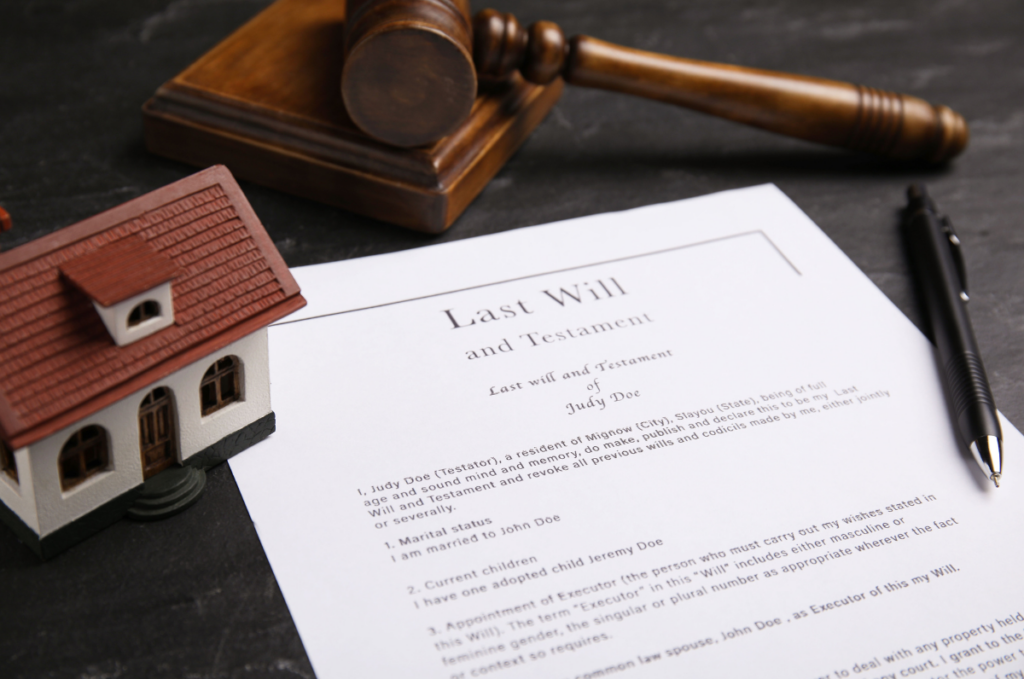 A stock photo for inheriting property: a last will and testament beside a gavel and a house figurine.