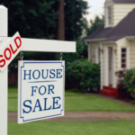 A "Sold" and "House for Sale" sign in the front yard of a home