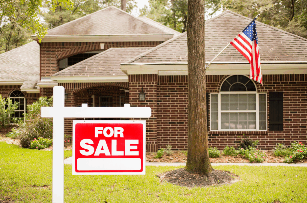A house with a "For Sale" sign in the front yard