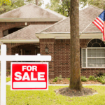 A house with a "For Sale" sign in the front yard