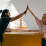A man and woman high-fiving over a packed box
