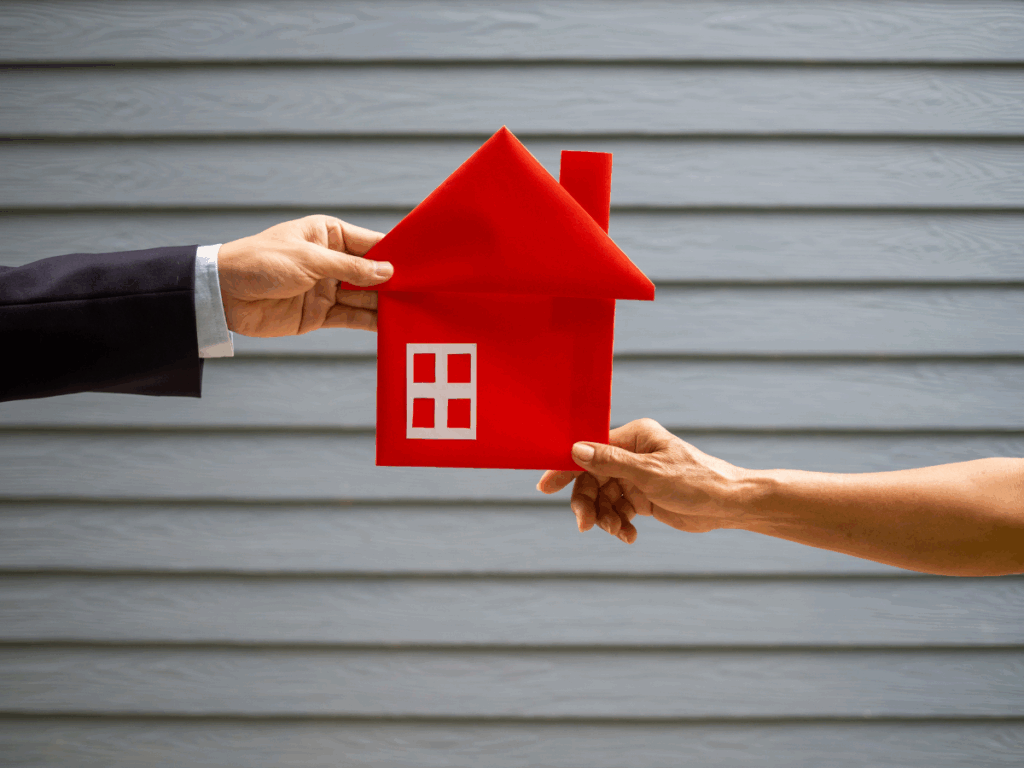 Two hands holding a red house cutout