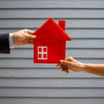 Two hands holding a red house cutout