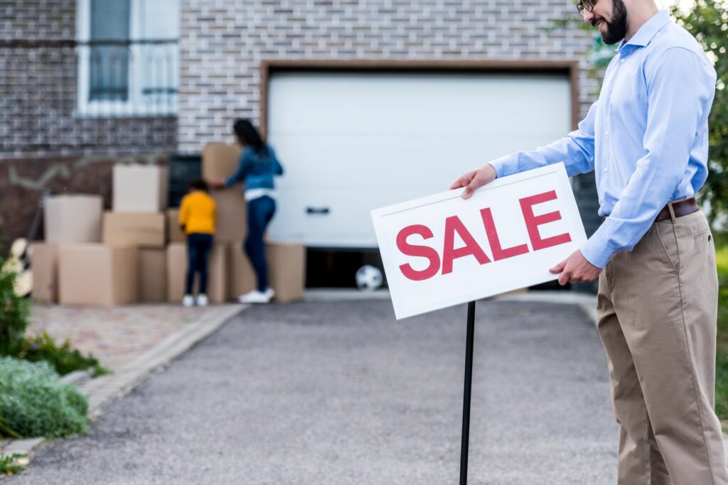 man holding a sale sign - house for sale as-is in Kansas City