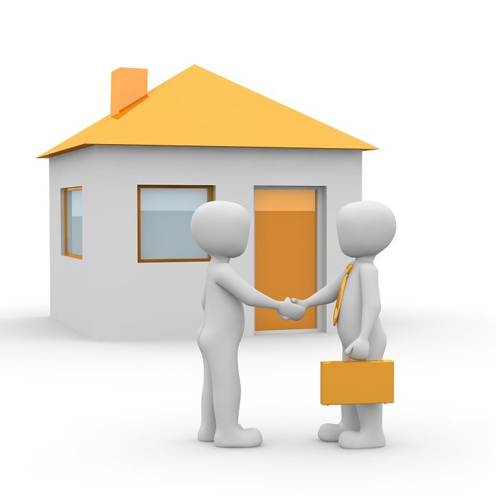 Two people shaking hands in front of a house