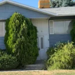 Modest single-family brick home in Salt Lake City with a 'For Sale' sign, representing foreclosure relief services.