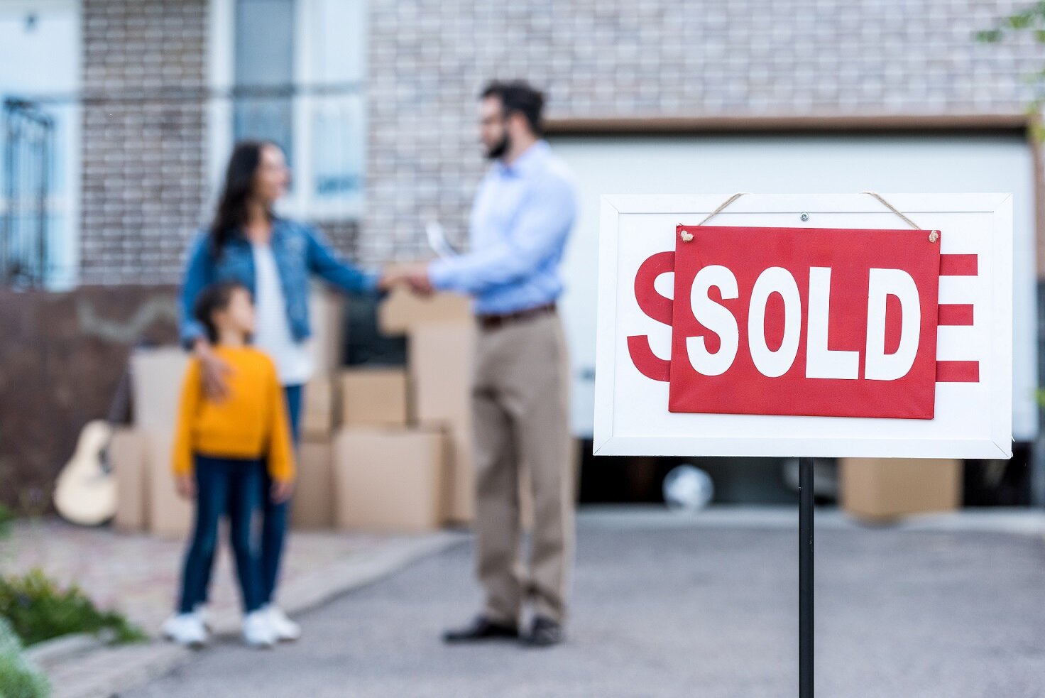 realtor making deal with single mother with sold signboard on foreground