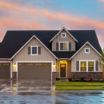 A beige suburban house with a wet driveway.